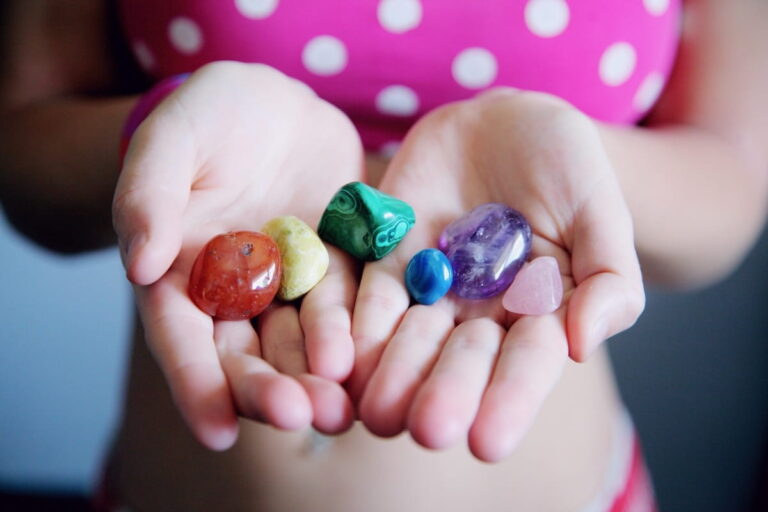 Hands holding healing crystals including rose quartz, malachite, and amethyst representing crystal healing practice"