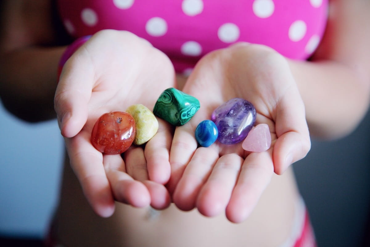 Hands holding healing crystals including rose quartz, malachite, and amethyst representing crystal healing practice"